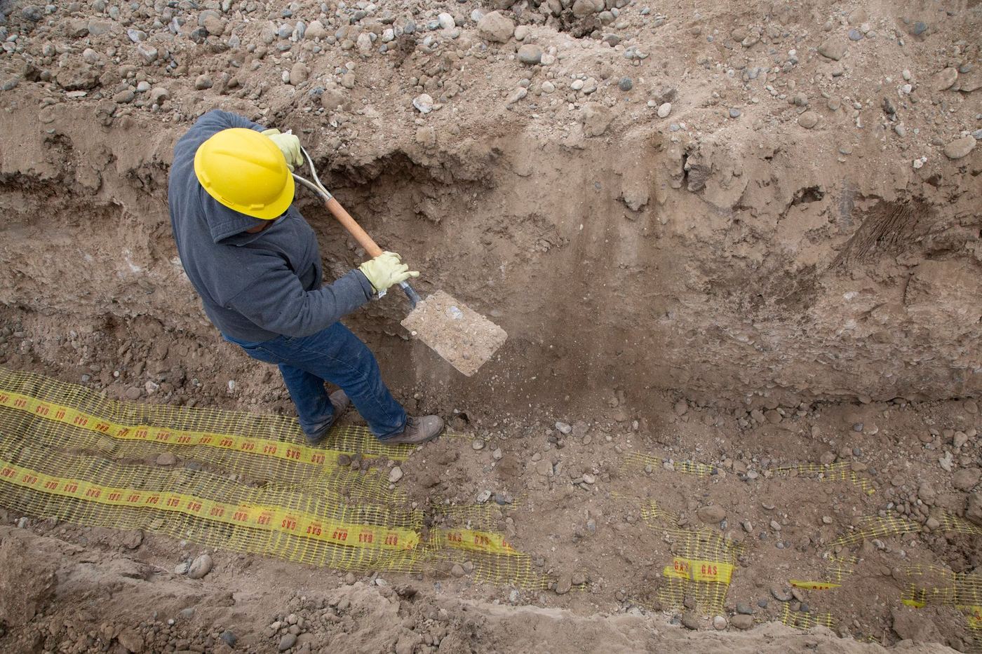Worker in a hard hat digging with a shovel